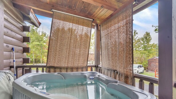 A hot tub with a wooden deck and a view of a white vehicle outside.