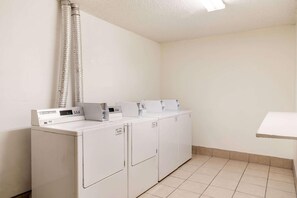 Convenient laundry facilities with four washing machines and a shelf for storage.