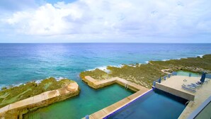 Ein Pool mit Blick auf den Ozean und felsiges Gelände.