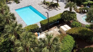 Área de piscina com espreguiçadeiras e vista para a praia e oceano.