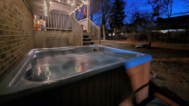 A hot tub with a wooden exterior, a staircase, and string lights.