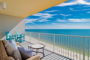 A balcony with a view of the ocean, a sofa, two chairs, and a small table. - Seawind 1406 | Gulf Shores, AL (Gulf Shores)