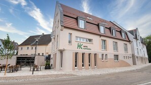 Ein Hotel mit sandfarbener Fassade, mehreren Fenstern und einem Ziegeldach.
