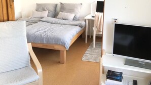 Une chambre à coucher avec un lit, une chaise, un téléviseur et un bureau.
