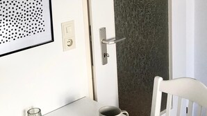 Une table blanche avec un vase en verre, une tasse et un magazine.