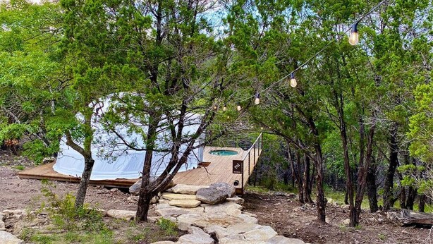 Entorno rústico al aire libre con una terraza de madera, un jacuzzi y un sendero de piedra.