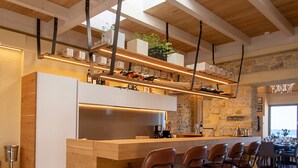Een moderne keuken met een houten bar, stenen muren en uitzicht op de omgeving.
