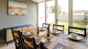 Un comedor con una mesa preparada para cuatro personas, un armario azul y un cuadro en la pared.