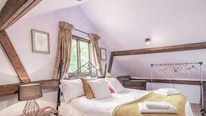 A cozy bedroom with a bed, a bedside table, a hanging light, and a window with curtains.