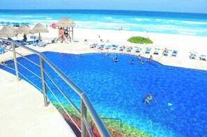 A pool area with clear blue water, lounge chairs, and a lifeguard stand. - Bright Oceanfront Retreat for 6 - Balcony & Beach Access - Villas Marlin (Cancún)