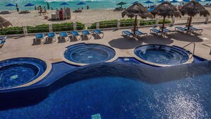 Un espace piscine doté de plusieurs bains à remous et de chaises longues.