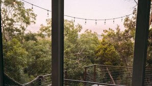 Una camera da letto con una grande finestra vista su una terrazza e una vasca idromassaggio.