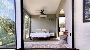 Una camera da letto con un letto, un ventilatore a soffitto e vista sull'esterno.