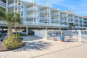 A multi-story hotel with balconies, a covered walkway, and outdoor seating areas.