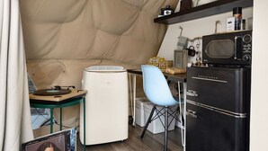 Eine kompakte Küche mit Kühlschrank, Mikrowelle und einer kleinen Essecke mit Stuhl und Tisch.