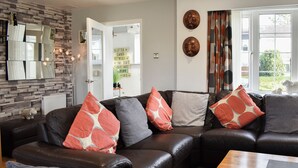 A living room with a sectional sofa, a coffee table, and a fireplace. - A lovely welcoming house with all the comforts of home. (Morfa Bychan)