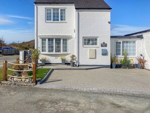 A two-story house with a paved driveway, a mailbox, and potted plants. - A lovely welcoming house with all the comforts of home. (Morfa Bychan)