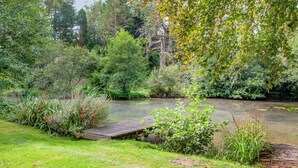 A natural landscape with a wooden bridge over a calm river, surrounded by lush greenery and trees. - 2 bedroom accommodation in Modbury (Modbury)