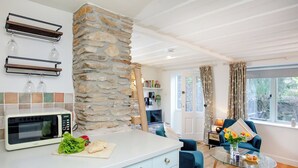 A modern kitchen with a stone accent wall, a microwave, and a cutting board with vegetables. - 2 bedroom accommodation in Modbury (Modbury)