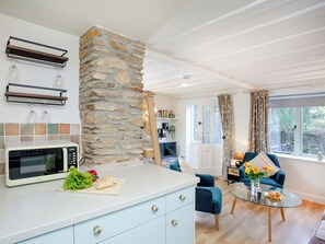 A modern kitchen with a stone accent wall, a microwave, and a cutting board with vegetables. - 2 bedroom accommodation in Modbury (Modbury)