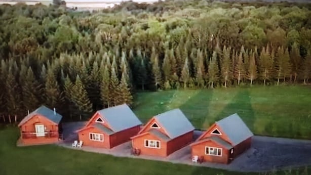 A cluster of red cabins with sloped roofs, surrounded by dense forest and mountains in the background. - Luxury Cabin #3 (Mars Hill)
