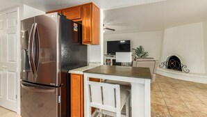 Een moderne keuken met een roestvrijstalen koelkast, houten kastjes en een klein eiland met barstoelen.