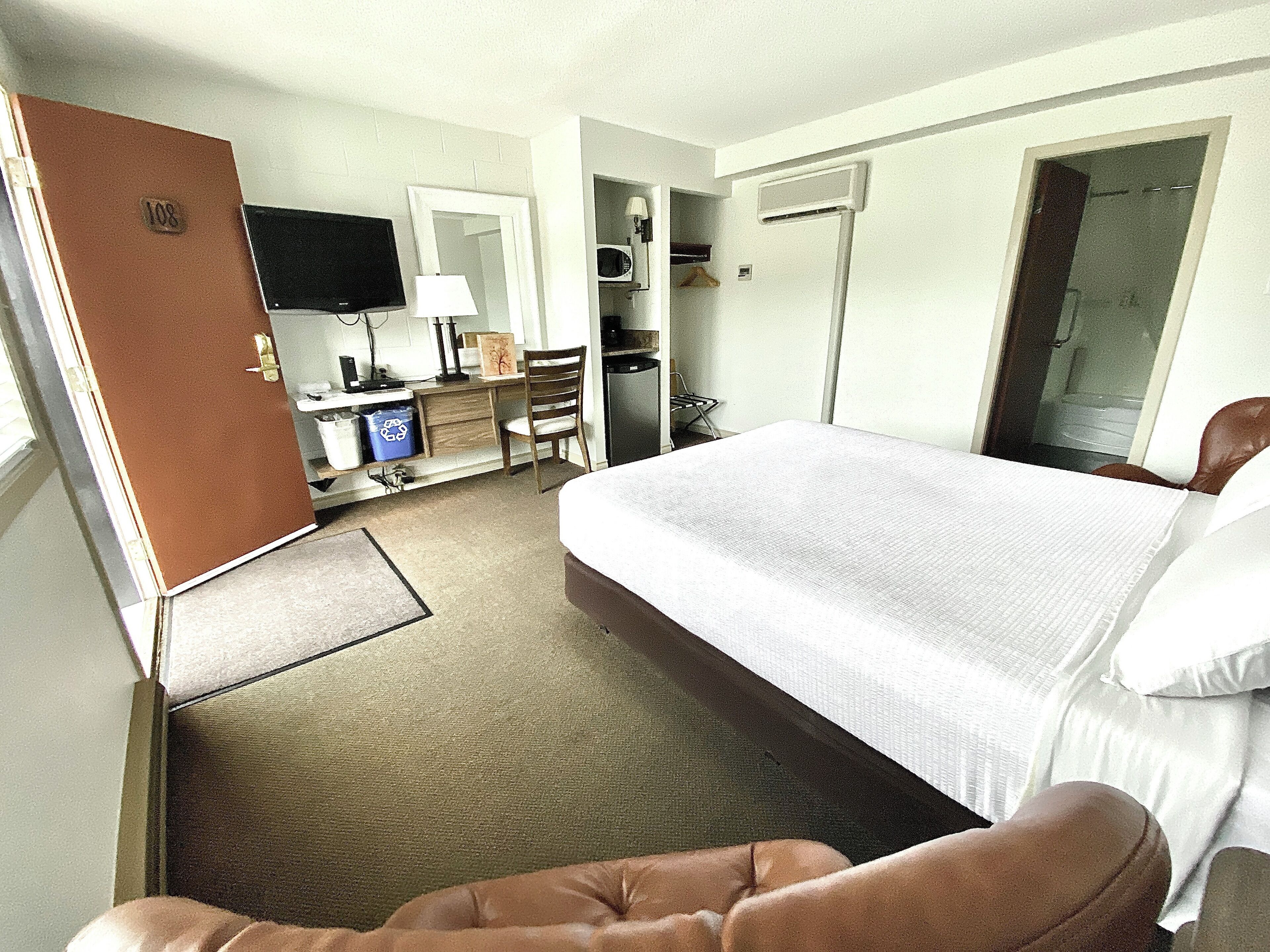 Une chambre d’hôtel avec un grand lit, un bureau avec une chaise, une télévision et une armoire.