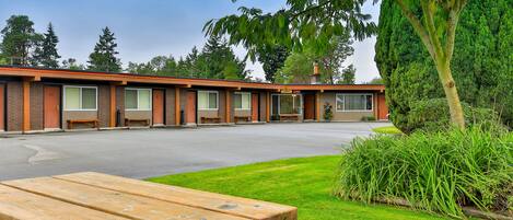 A motel with a row of rooms, a parking lot, and a picnic table in the foreground.