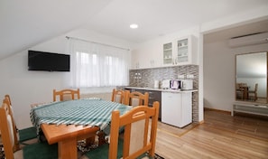 Enjoy meals in the dining area with a table and chairs, a TV on the wall, and a kitchenette with modern appliances.