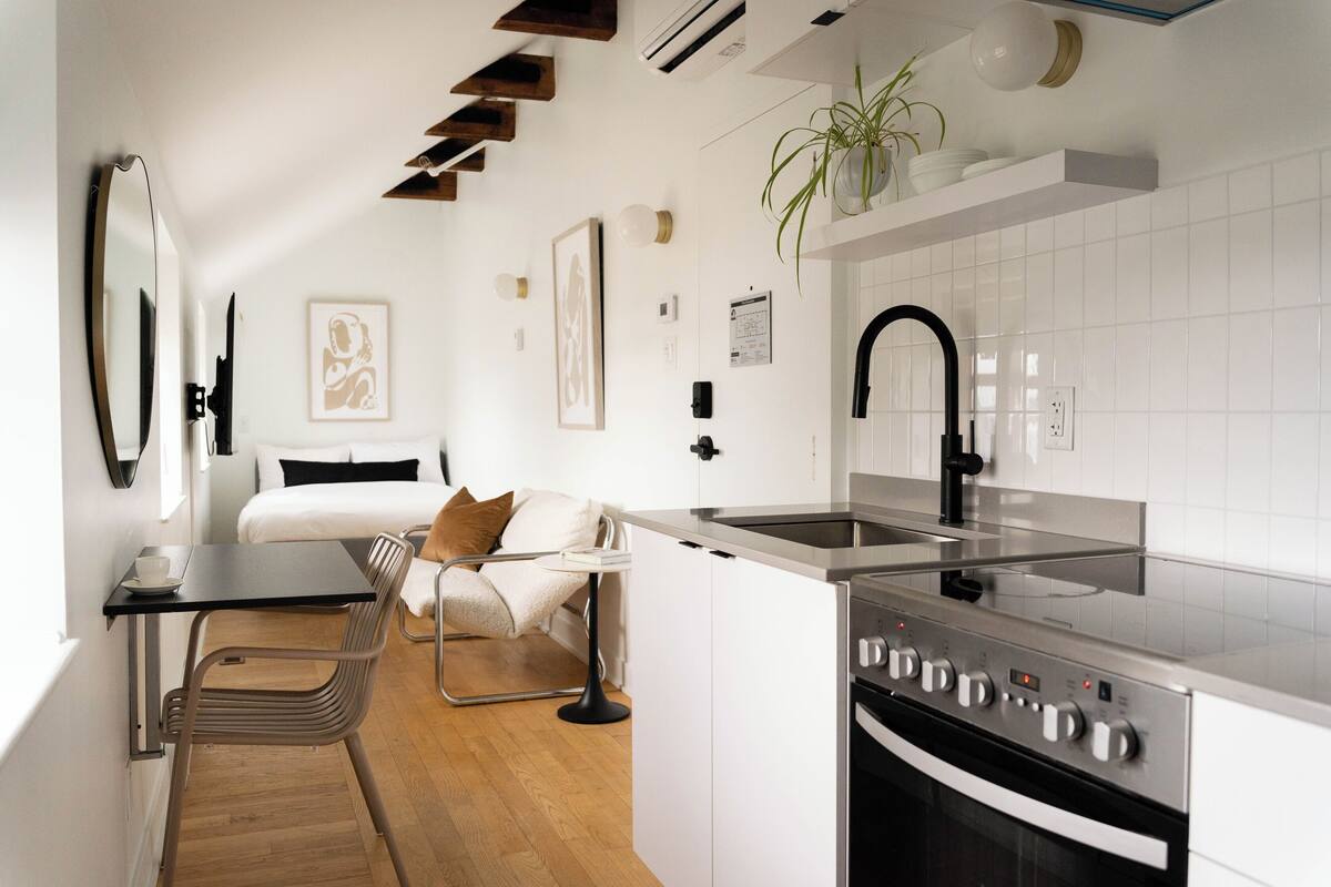 A compact kitchen with a modern stove, a sink, and a dining area with a chair and table.