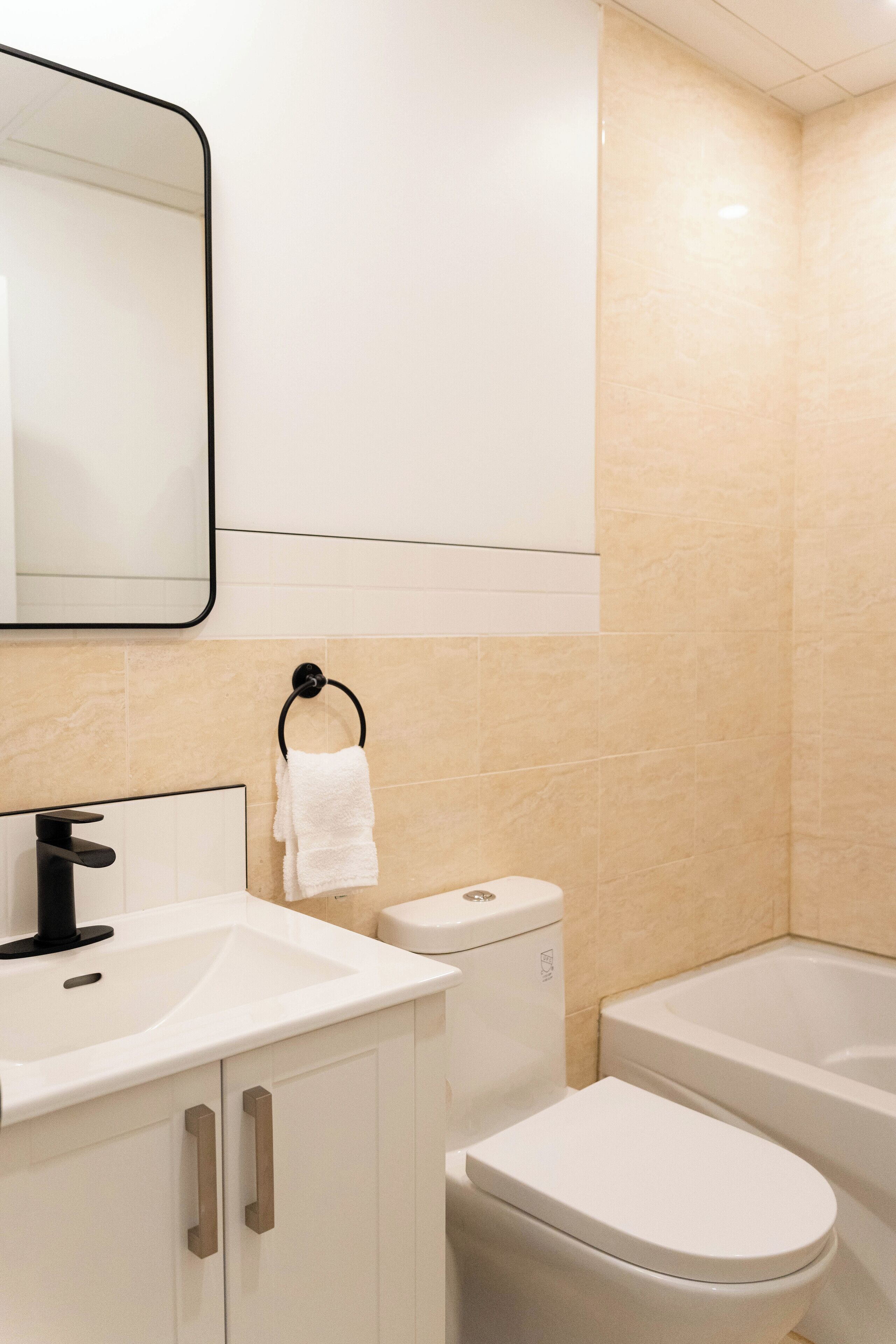 Un baño moderno con lavamanos, inodoro y bañera blancos.