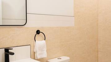 Un baño moderno con lavamanos, inodoro y bañera blancos.