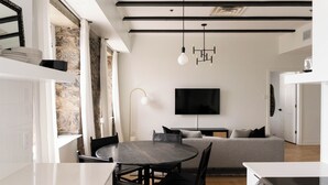 A modern kitchen with a dining area, a stone wall, and a flat-screen TV. - Maison Rasco by Luxury In Transit (Montreal)