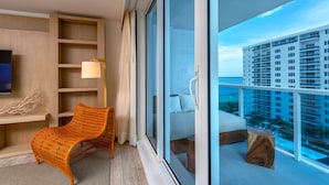 Une chambre d’hôtel moderne dotée d’une grande porte-fenêtre coulissante donnant sur un balcon avec vue sur la ville.