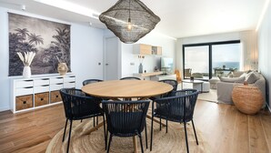 Un comedor moderno con una mesa redonda de madera, sillas tejidas negras y una lámpara colgante de diseño.
