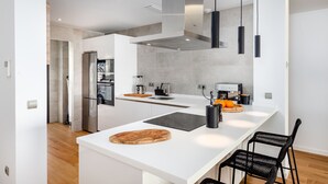 Una cocina moderna con isla central, electrodomésticos integrados e iluminación colgante.