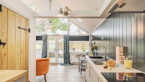 Une cuisine moderne avec une porte en bois, un coin repas avec une chaise et une vue sur l’extérieur.