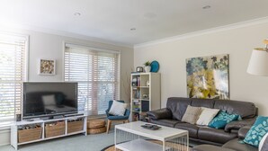 Ein modernes Wohnzimmer mit Flachbildfernseher, Sofa, Couchtisch und Bücherregal.