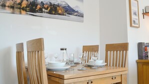 A dining table with chairs, plates, glasses, and a pitcher.