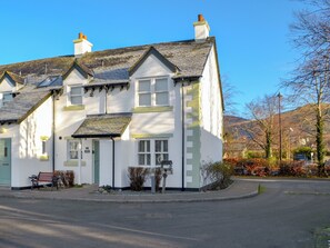 A white building with a green door, a bench, and a small garden area. - 2 bedroom accommodation in Keswick (Keswick)
