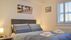 A bedroom with a bed, bedside tables, and artwork on the walls.