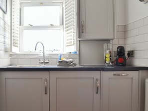 Et køkken med et vindue, en vask og en kaffemaskine.