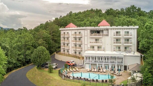 Un hôtel à plusieurs étages doté d’un espace piscine, entouré d’une végétation luxuriante.