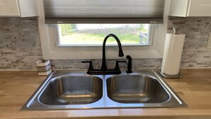 A kitchen with a double stainless steel sink, a black faucet, and a window with blinds.