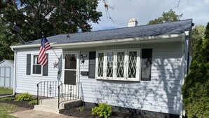 A single-story house with a front porch, a flag, and a mailbox.