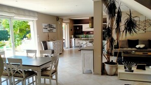 Un vaste espace de vie comprenant une table et des chaises, un canapé et une grande plante en pot.