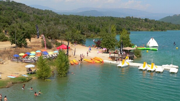 Une plage avec des canoës, des kayaks et une petite cabane.