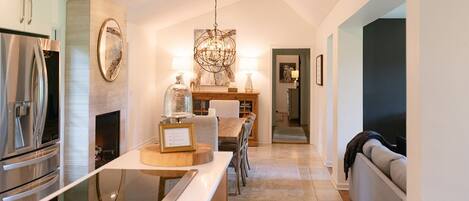 A modern kitchen with a central island, stainless steel appliances, and a chandelier.