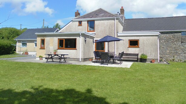 Een tweelaags huis met een patio, inclusief een tafel, stoelen en een parasol.