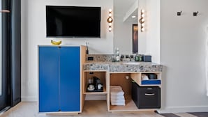 A modern bathroom with a large mirror, vanity, and a flat-screen TV. - The Hotel Castro San Francisco (San Francisco)
